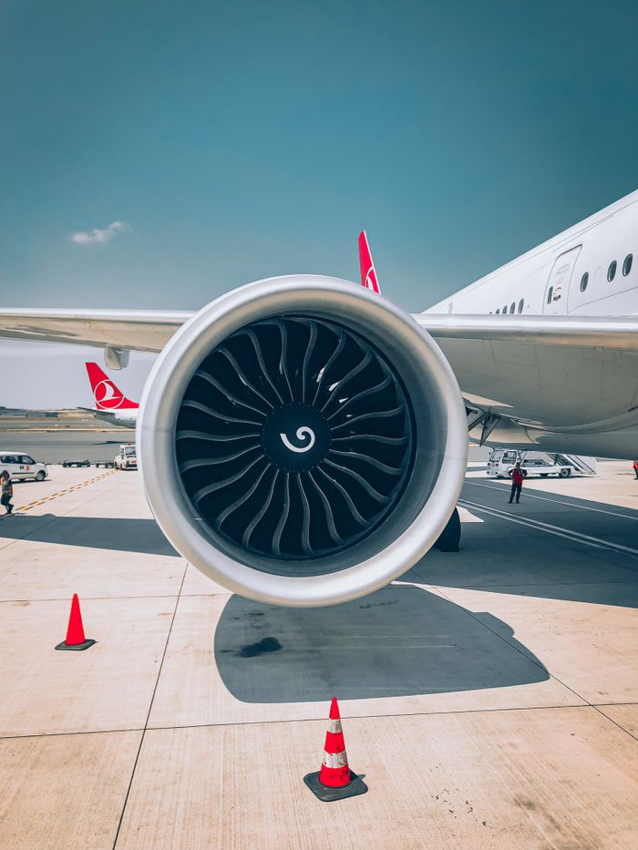 Mastering the First Impression: Your intriguing post title goes here Detailed view of a jet engine on an airport runway with safety cones and clear sky.