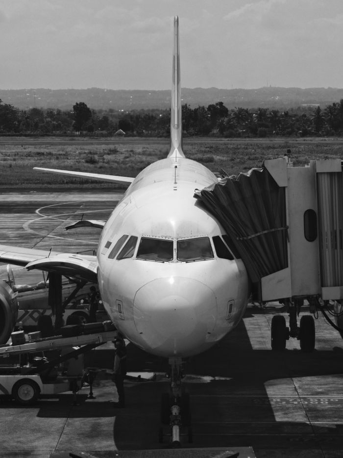 Crafting Captivating Headlines: Your awesome post title goes here Monochrome image of an airplane docked at an airport gate, ready for boarding.